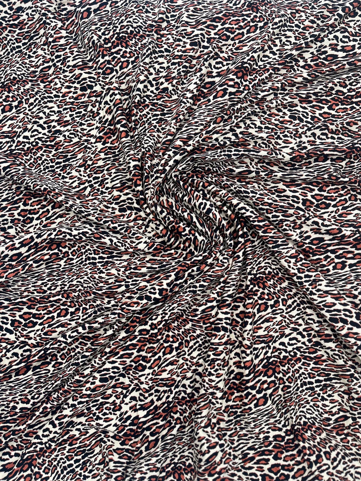 Animal print jersey fabric in cream, black, and rust colors.
